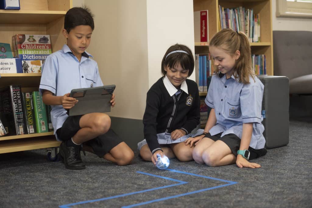 Junior School students at Malvern Campus doing STEM activities with a robot and laptop 2022