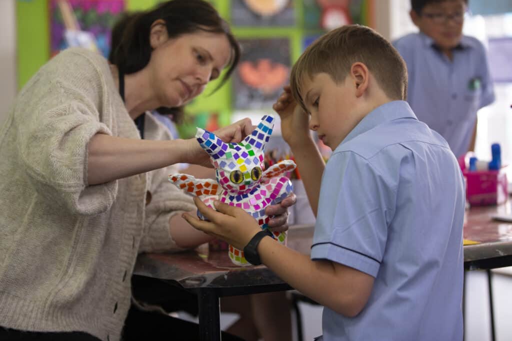 Primary school boy explores elements of art with teacher.