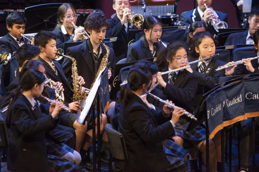 High school students playing musical instruments together on stage